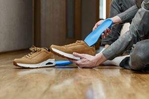 Man putting new custom insole in a shoe. Feet recreation medicine concept