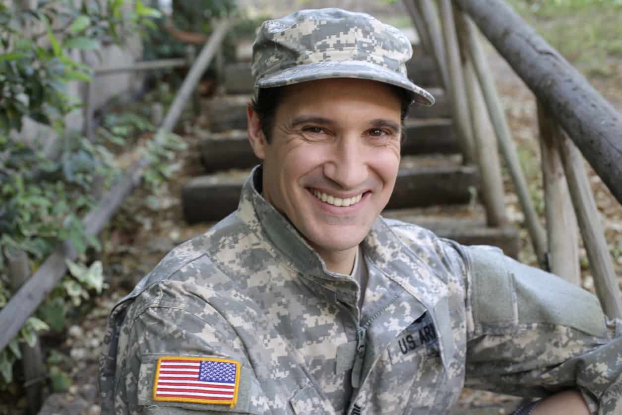 A caucasian army soldier in his 30s is wearing a traditional USA army uniform with cap.
