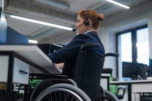 Red-haired caucasian woman in a wheelchair talking on a headset.