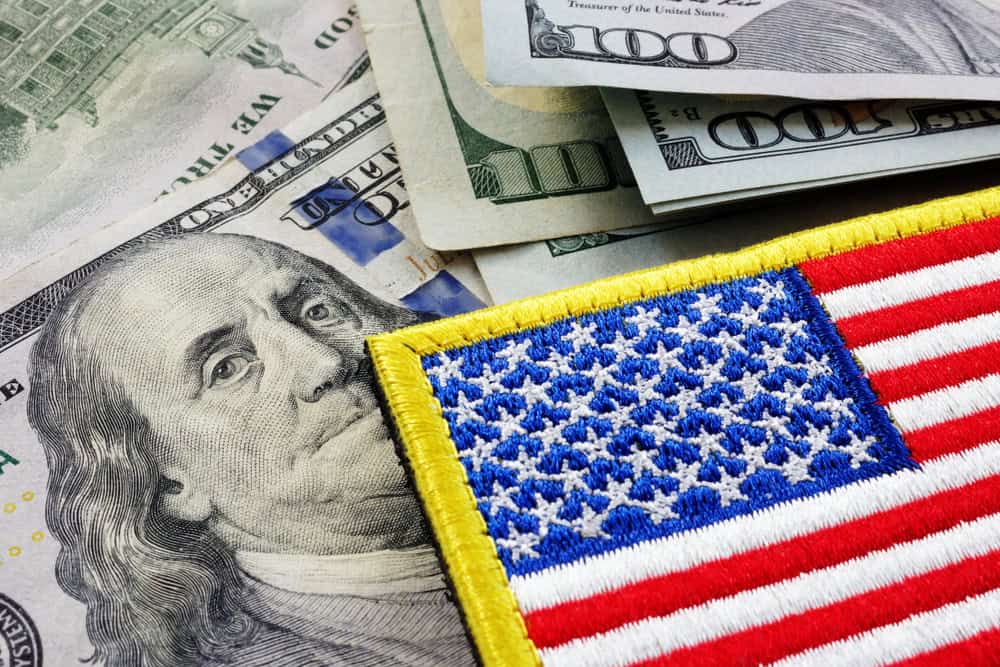 Close-up of U.S. dollar bills with an American flag patch placed on top