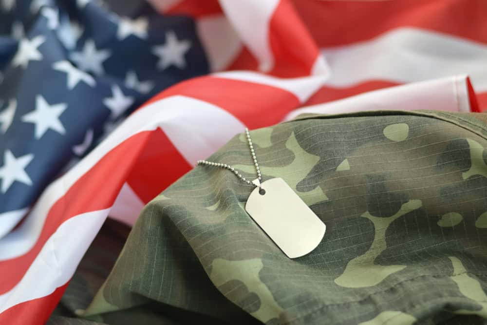 VA benefits for Gulf War veterans represented by military dog tags placed on a camouflage uniform with the American flag in the background.