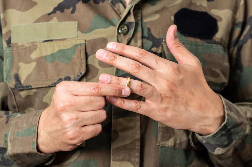 VA benefits for Gulf War veterans illustrated by a service member in uniform removing a wedding ring to represent the personal impact of military service.