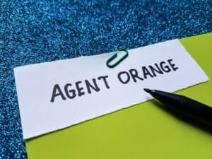 Agent Orange exposure and aggressive bone marrow cancers concept with labeled note and pen.