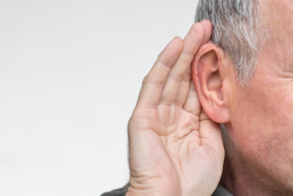 Man holding his hand to his ear, illustrating hearing difficulty related to VA benefits for tinnitus.